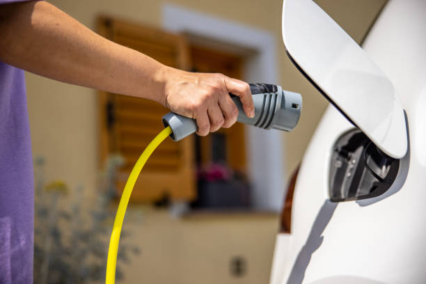 istock Woman plugging a charger to electric car socket 1354069704