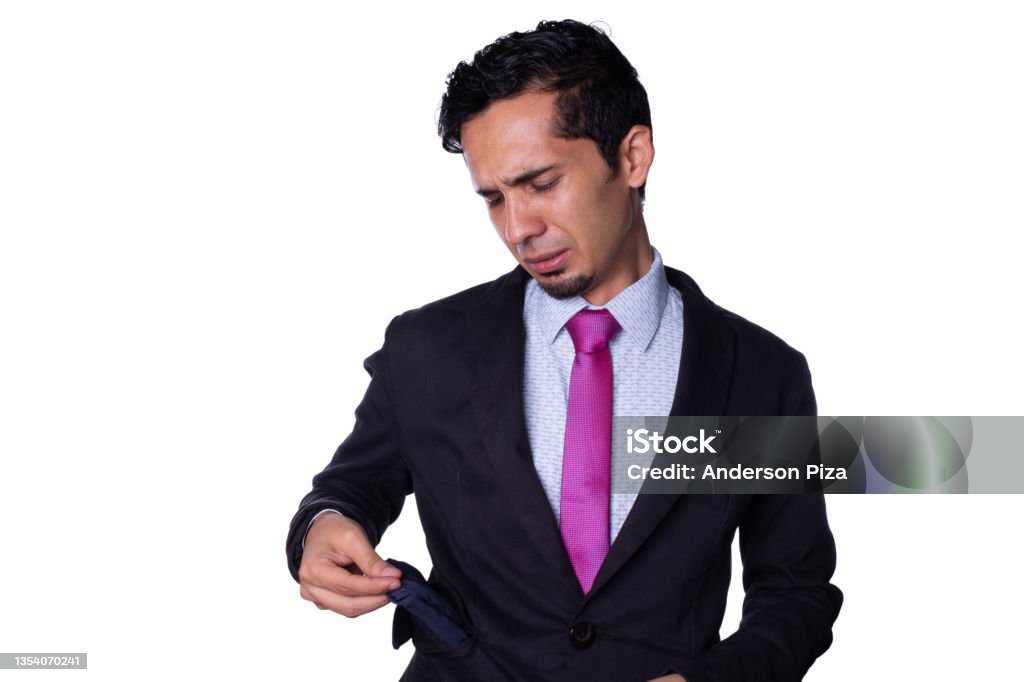 Businessman sad because he ran out of money. Young adult latin young man pulling out empty pocket of his suit jacket, isolated on all white background. 25-29 Years Stock Photo