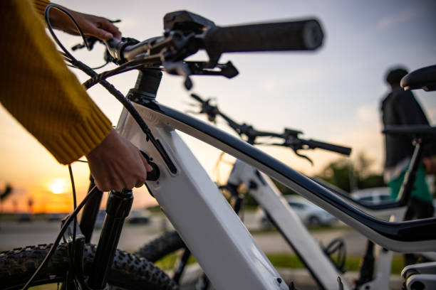 gros plan de la main de la femme insérant une prise dans un vélo électrique pour la recharger - electric bicycle photos et images de collection