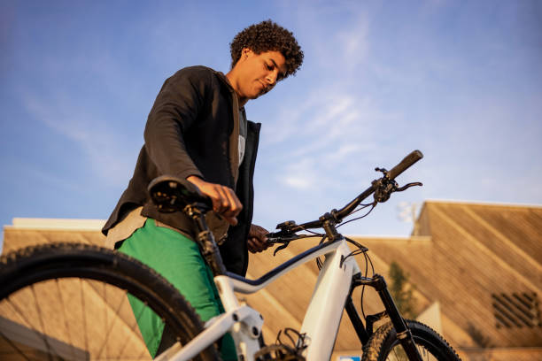 istock Low angle view of young man standing with electric bicycle 1354071602