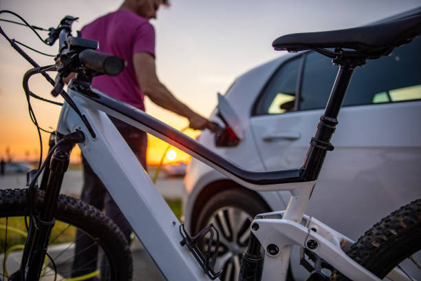 Man inserting electric plug into car for charging Man inserting electric plug into car for charging at electric vehicle charging station alternative fuel vehicle stock pictures, royalty-free photos & images