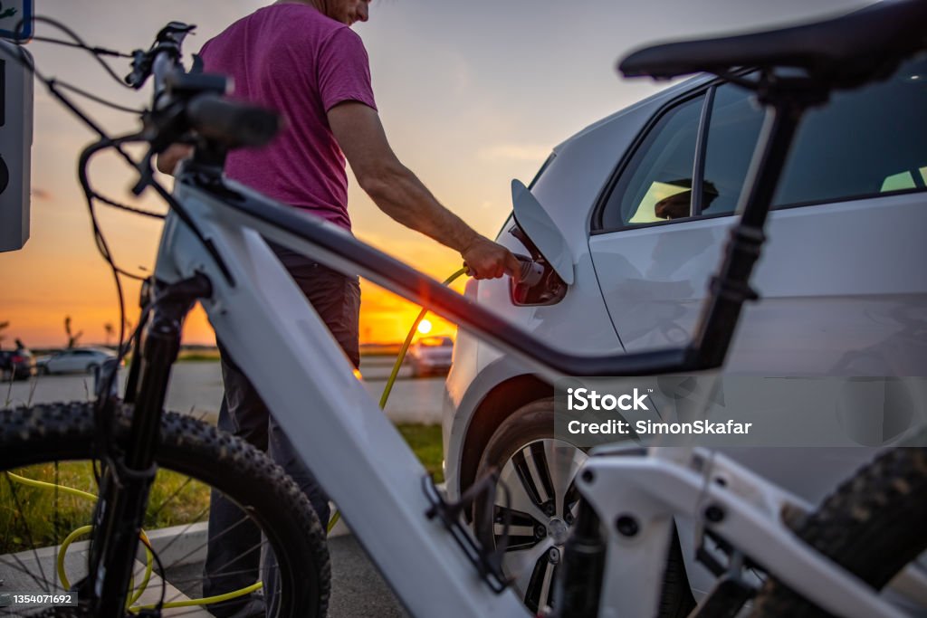 Man inserting electric plug into car for charging Man inserting electric plug into car for charging at electric vehicle charging station Electric Car Stock Photo