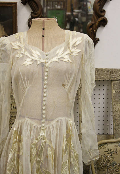 Among many antique objects, an antique dress is photographed.