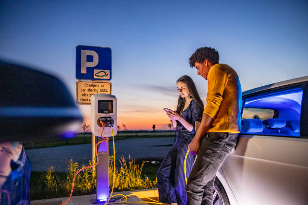 istock Couple using mobile phone while their electric car is charged 1354072911