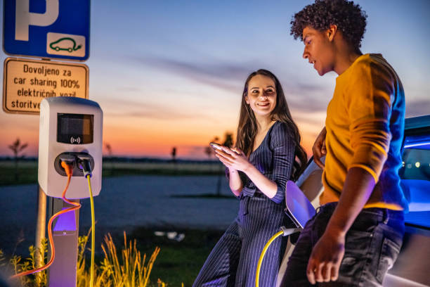 istock Couple using mobile phone while their electric car is charged 1354072953