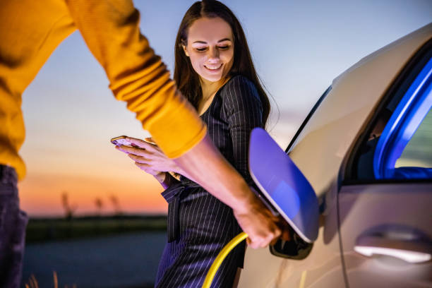 Couple charging their car at night stock photo