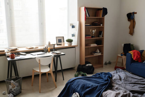 istock Modern minimalistic students room with awards on shelves, unmade bed with blanket and office supplies on desk 1354075261
