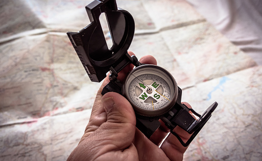 Hand with military compass and a map in the background