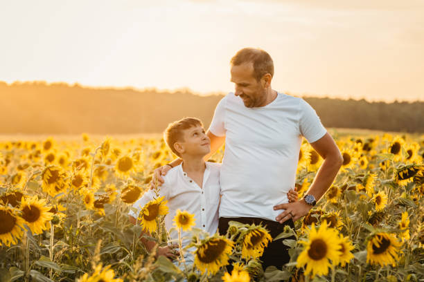 istock Father and son looking at each other in sunflowers field 1354076112