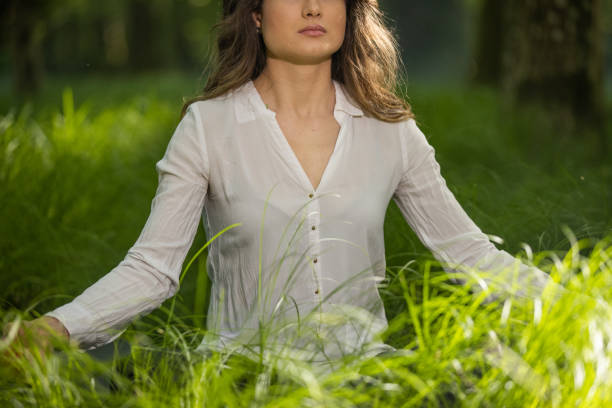 istock Midsection of woman practicing yoga at forest 1354077312