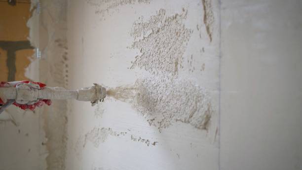 Machine application of plaster to the wall. Plasterer throws plaster on the wall. Plastering walls in a new house. Machine application of mortar to the wall stock photo