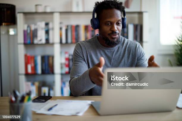 Man With Bluetooth Headphones Having Video Call On Laptop Computer In His Home Office Stock Photo - Download Image Now
