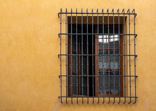 istock Window with iron grille and yellow wall. 1354077874