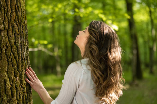 istock Young woman touching tree trunk with eyes closed 1354077881