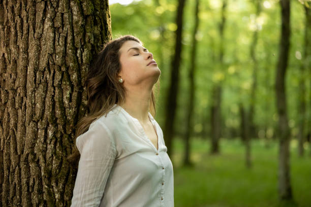 istock Beautiful young woman leaning on tree 1354078757