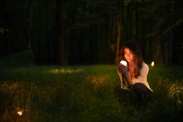 Beautiful woman crouching and holding glowing object in forest