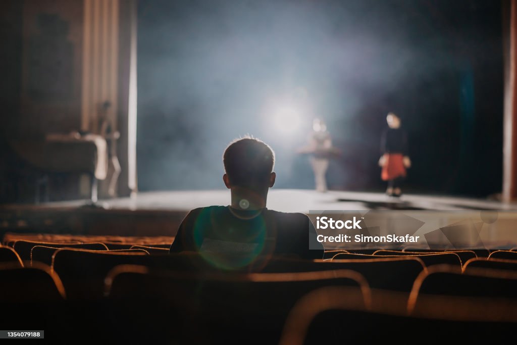 One spectator watching the rehearsal of ballet dancer on stage One spectator sitting and watching the rehearsal of ballet dancer on stage Theatrical Performance Stock Photo