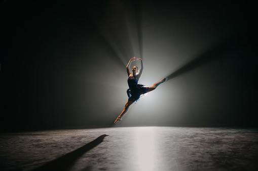Backlit shot of ballerina rehearsing on the stage