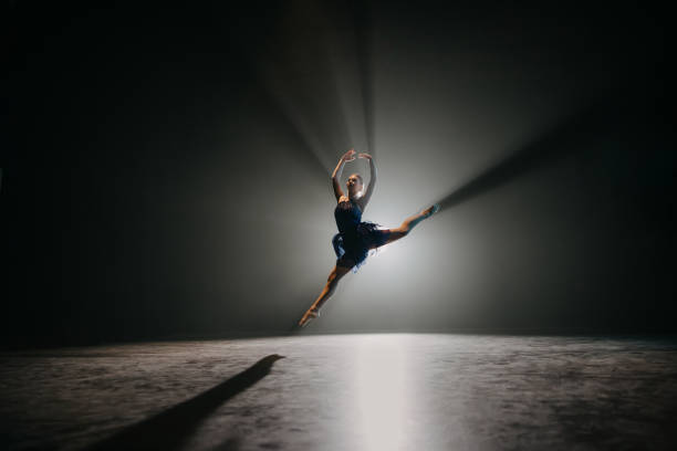 Ballerina rehearsing on stage Backlit shot of ballerina rehearsing on the stage color image performing arts event performer stage theater stock pictures, royalty-free photos & images