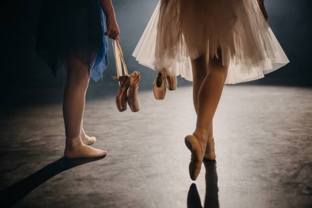 Two ballerinas carrying her ballet shoes while walking on the stage Two ballerinas carrying her ballet shoes while walking on the stage illuminated with spotlights backstage photos stock pictures, royalty-free photos & images