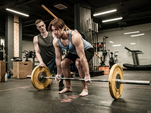 istock Young Man lifting weights with his trainer in the Gym 1354081102