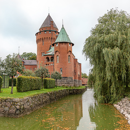 Hjularod is a romantic red castle with tall towers surrounded by a moat, Eslov, Sweden, September 16, 2021