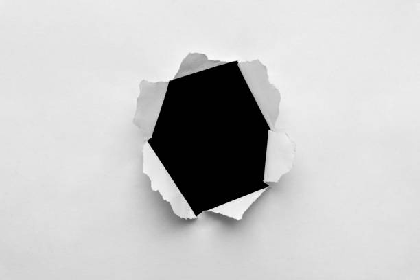 istock Torn hole in the sheet of paper with black background 1354081728