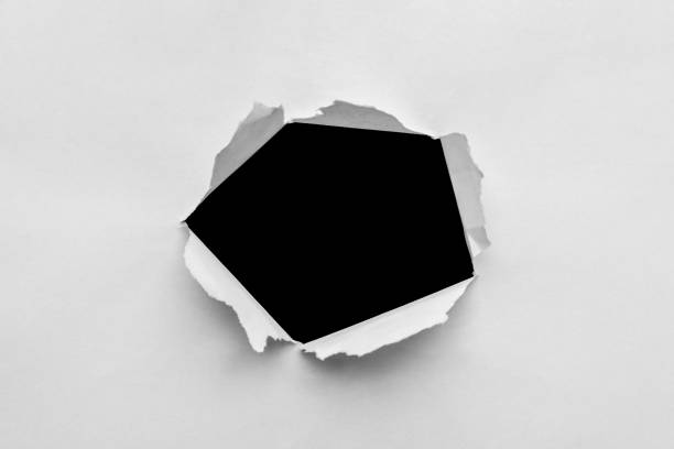 istock Ragged hole torn in paper on black background 1354081735
