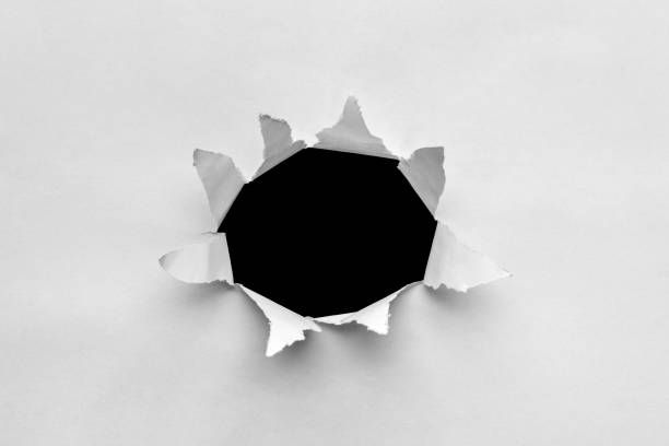 istock Hole torn in ripped paper on black background 1354081736