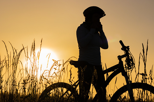 Female cyclist wearing bicycle helmet on field during sunset
