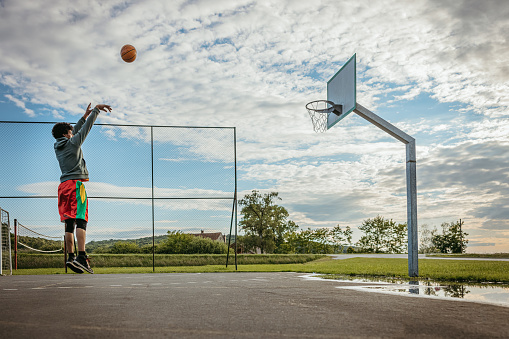 Basketball player practicing free throws at outdoor sports court