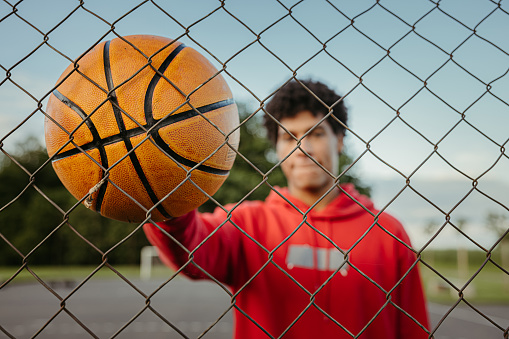 Basketball player standing with ball at outdoor sports court