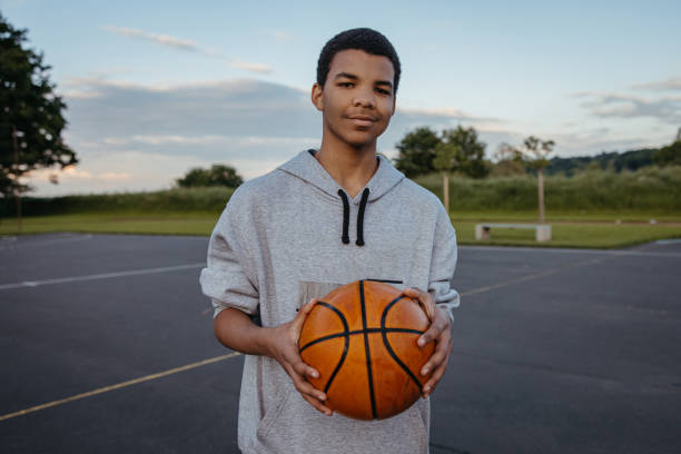 Basketball player with ball Basketball player standing with ball at outdoor sports court one teenage boy only stock pictures, royalty-free photos & images