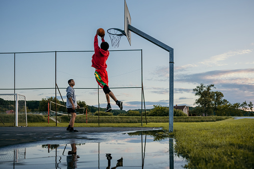 Two players practicing basketball on outdoor sports court