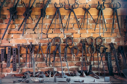 Blacksmith tools and horseshoe hanging on brick wall at workshop