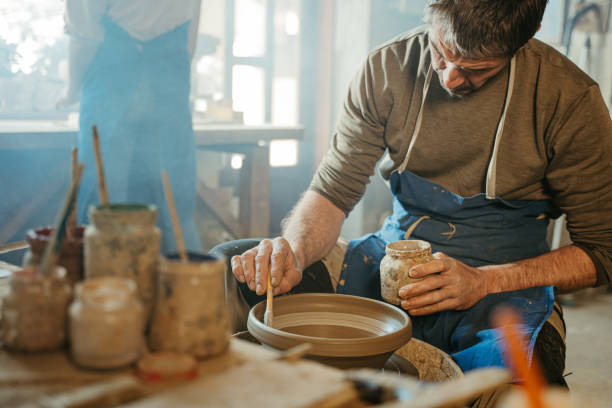 istock Potter coloring small bowl on potter's wheel 1354084970