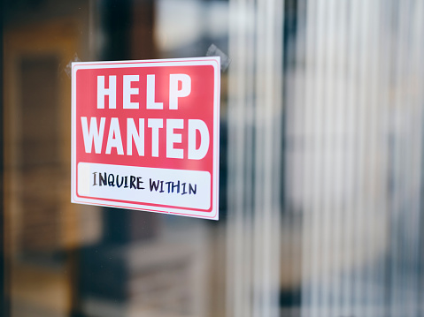 A small business help wanted sign in a window.
