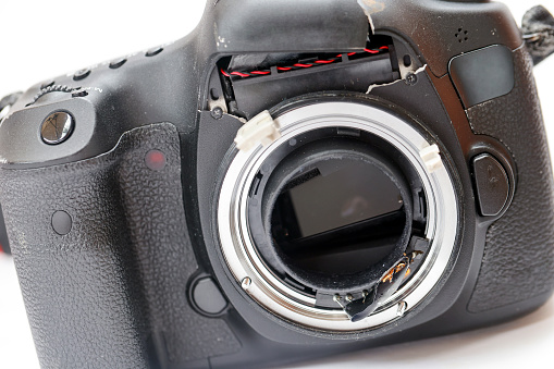 Damaged DSLR camera, front view, background with copy space, full frame horizontal composition