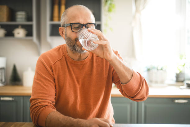 mature adult man drinking water - drinking water stockfoto's en -beelden