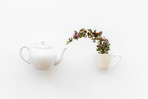 Tea concept with white teapot and dry tea leaves.