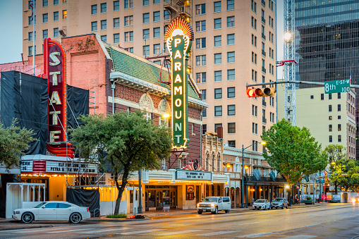 Theater marquees and cars on Congress Avenue in downtown Austin, Texas, USA at dawn.