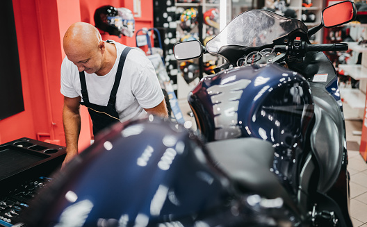Repairman repairs motorcycle in store