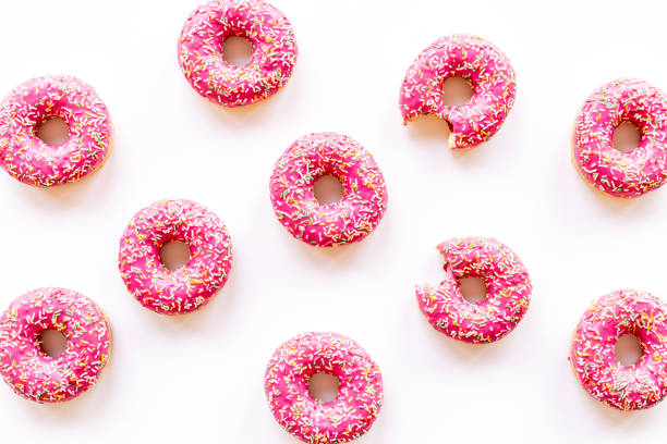 istock Pink frosted donuts with colorful sprinkles. Bakery background 1354099165
