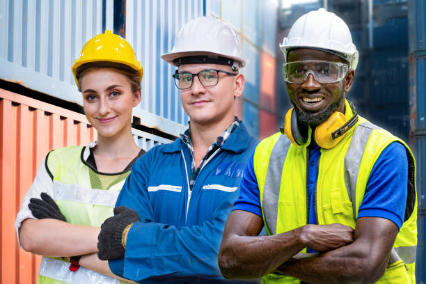 istock group workers engineering standing with confident with blue working suite dress and safety helmet in front of container background. Concept of smart industry worker operating. 1354102548