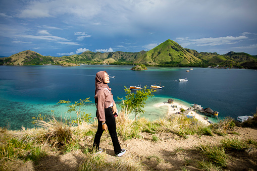Asian Muslim woman standing on hill watching sea