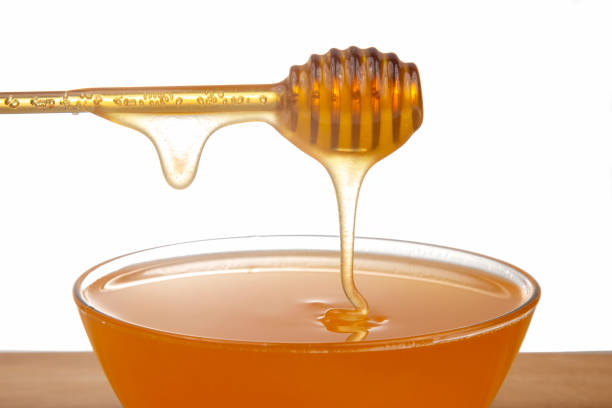 istock fresh honey dripping from a spoon into a transparent plate on a white background. organic vitamin health food 1354113502