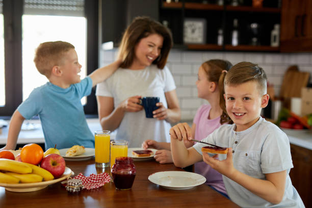 istock Mother and three kids in the kitchen eating breakfast 1354125018