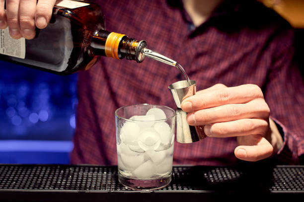 istock A young bartender is preparing a cocktail in a glass with ice, pouring liquor into a jigger. 1354127420