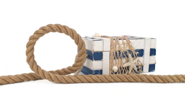 Thick rope next to blue and white striped box chest covered with fishing net, decorated with starfish and shells. Marine theme still life isolated on white background