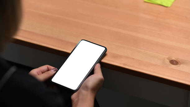 istock Over shoulder view of female holding mock up mobile phone with empty display. 1354139552
